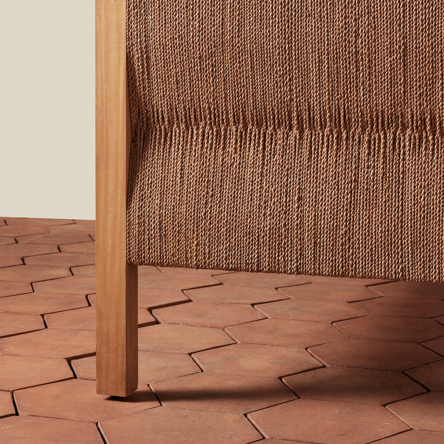 Close-up of a woven brown chair with a textured wall and patterned floor.- Number 5