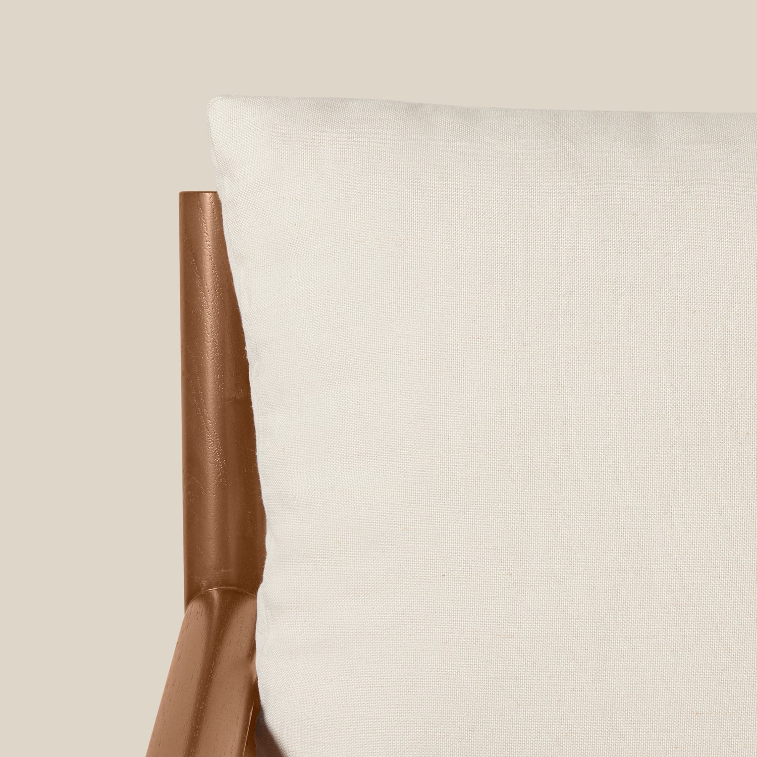 Close-up of a white textured cushion next to a brown leather chair arm against a solid beige background.- Number 6