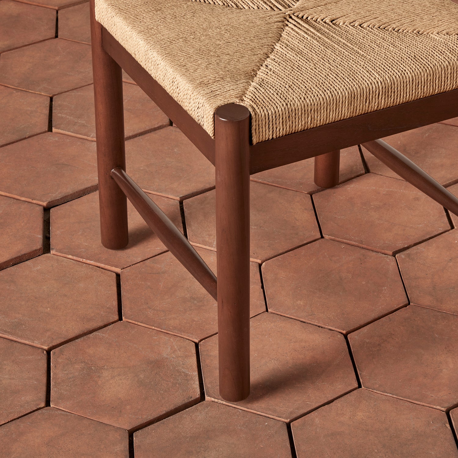 Brown hexagonal tiles on a floor with a wooden chair.- Number 8