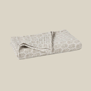 A folded textured blanket in a light beige and gray pattern, shown on a solid beige background. - Number 1