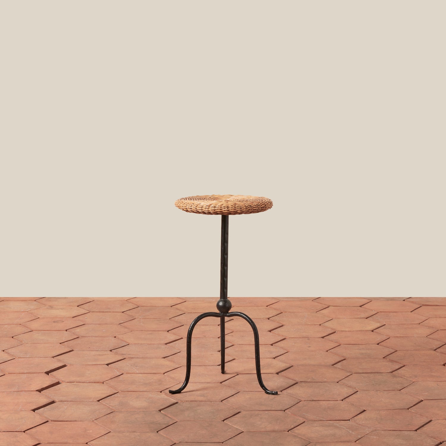 Small round table with woven top and metal legs on a wooden floor.- Number 1