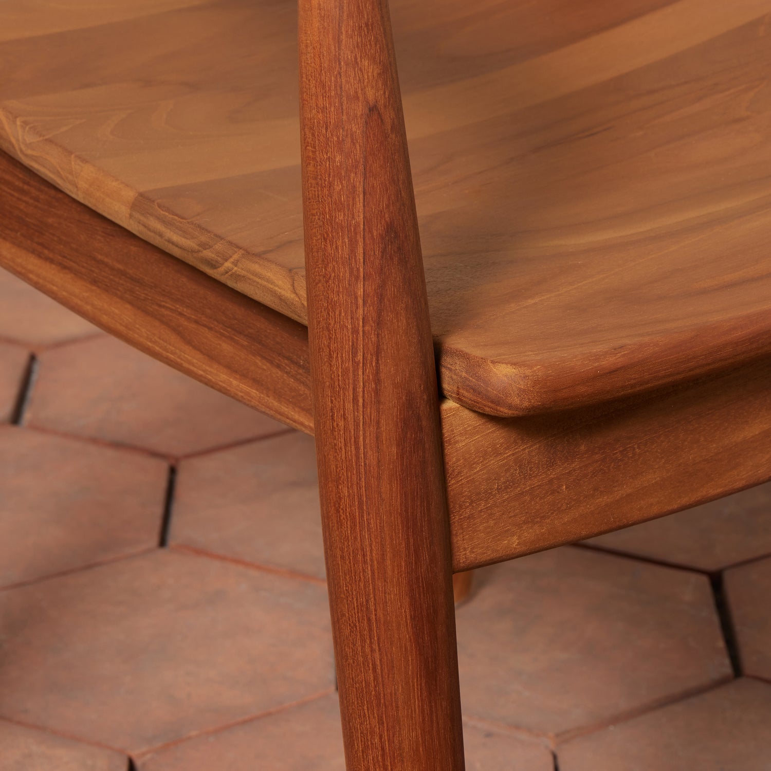 Close-up of a wooden chair with a textured floor in the background- Number 9