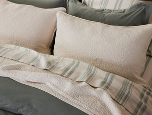 Textured pillows with a striped blanket on a bed - Number 4