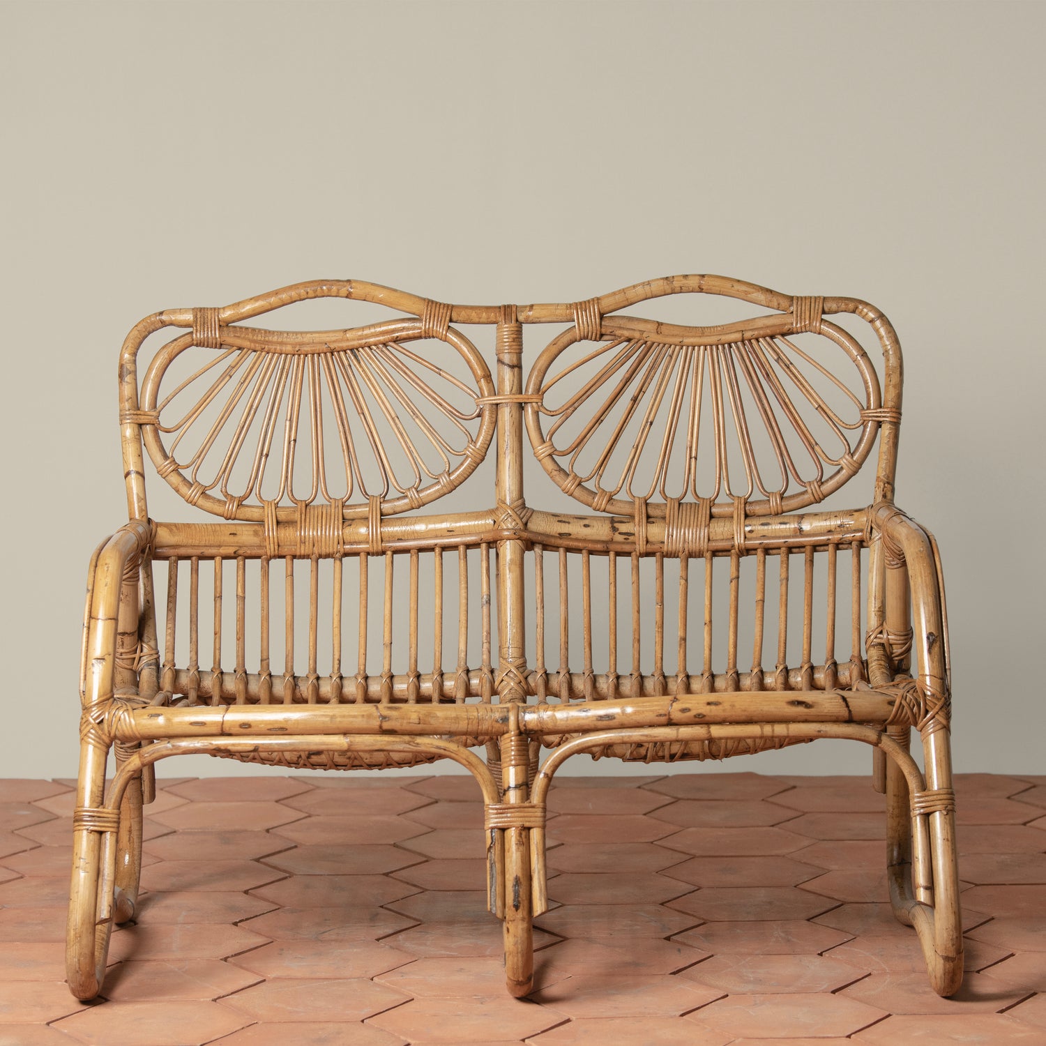 front facing angle of vintage rattan loveseat on tiled floor- Number 2