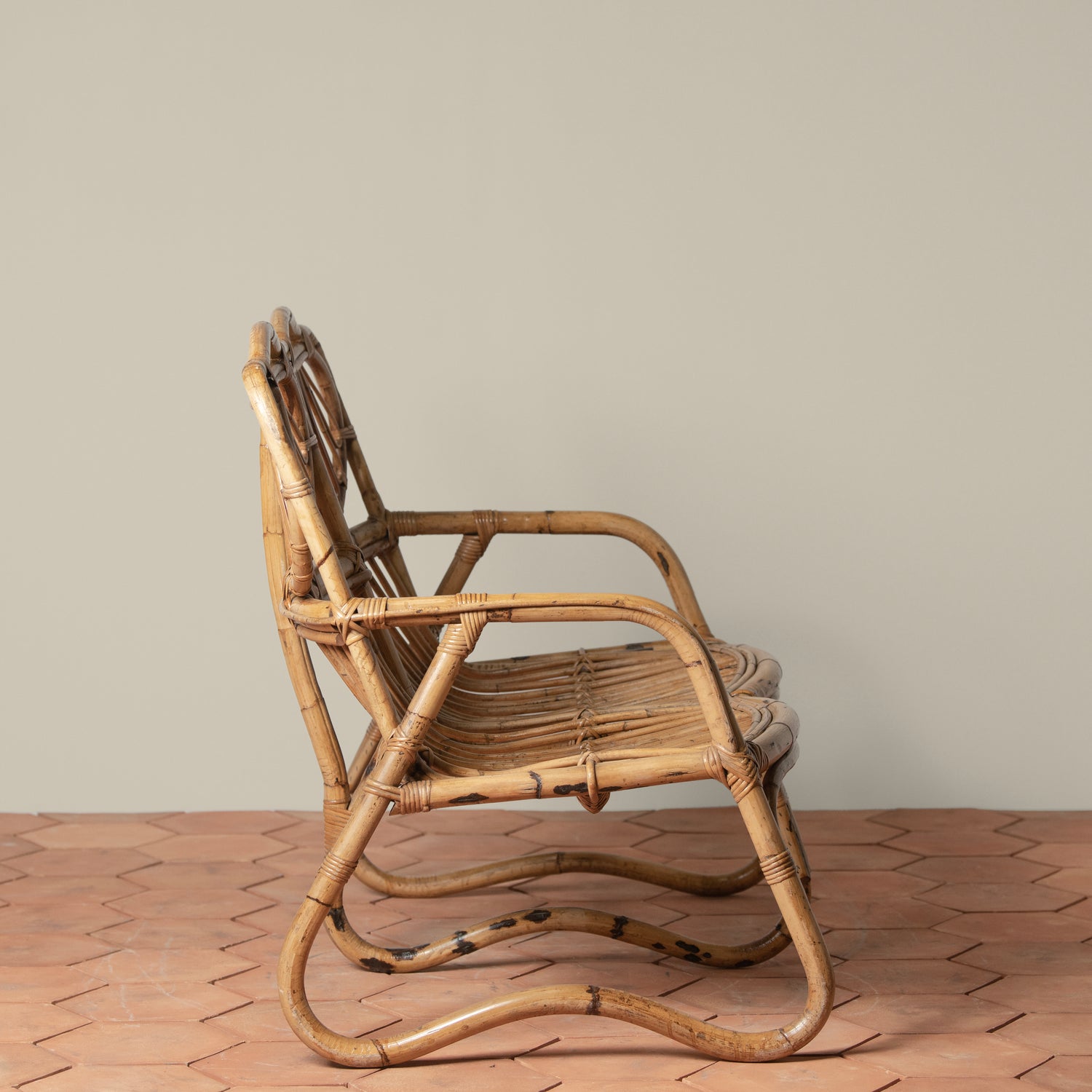 side angle of vintage rattan loveseat on tiled floor- Number 3