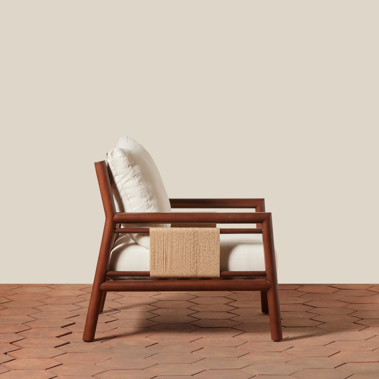 Wooden armchair with a white cushion and woven side on a wooden floor.- Number 2