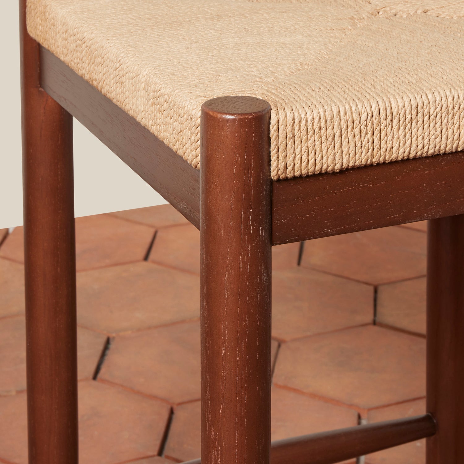 Close-up of a wooden chair with a woven seat on a terracotta-tiled floor.- Number 6