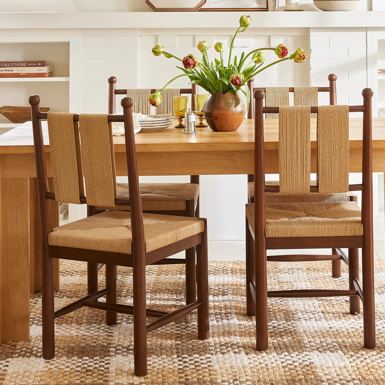 Dining room with wooden table and chairs, floral arrangement, and framed pictures on the wall.- Number 2
