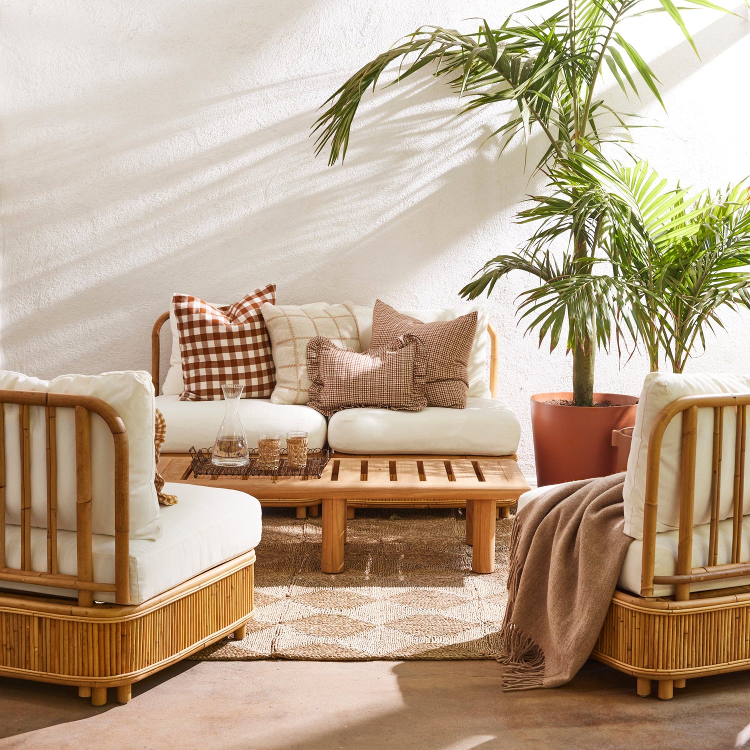 Outdoor seating area with wicker chairs, a sofa, and a coffee table with decorative items.- Number 2