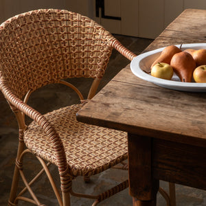 Wicker chair next to a wooden table with a plate of fruit in a kitchen. - Number 2