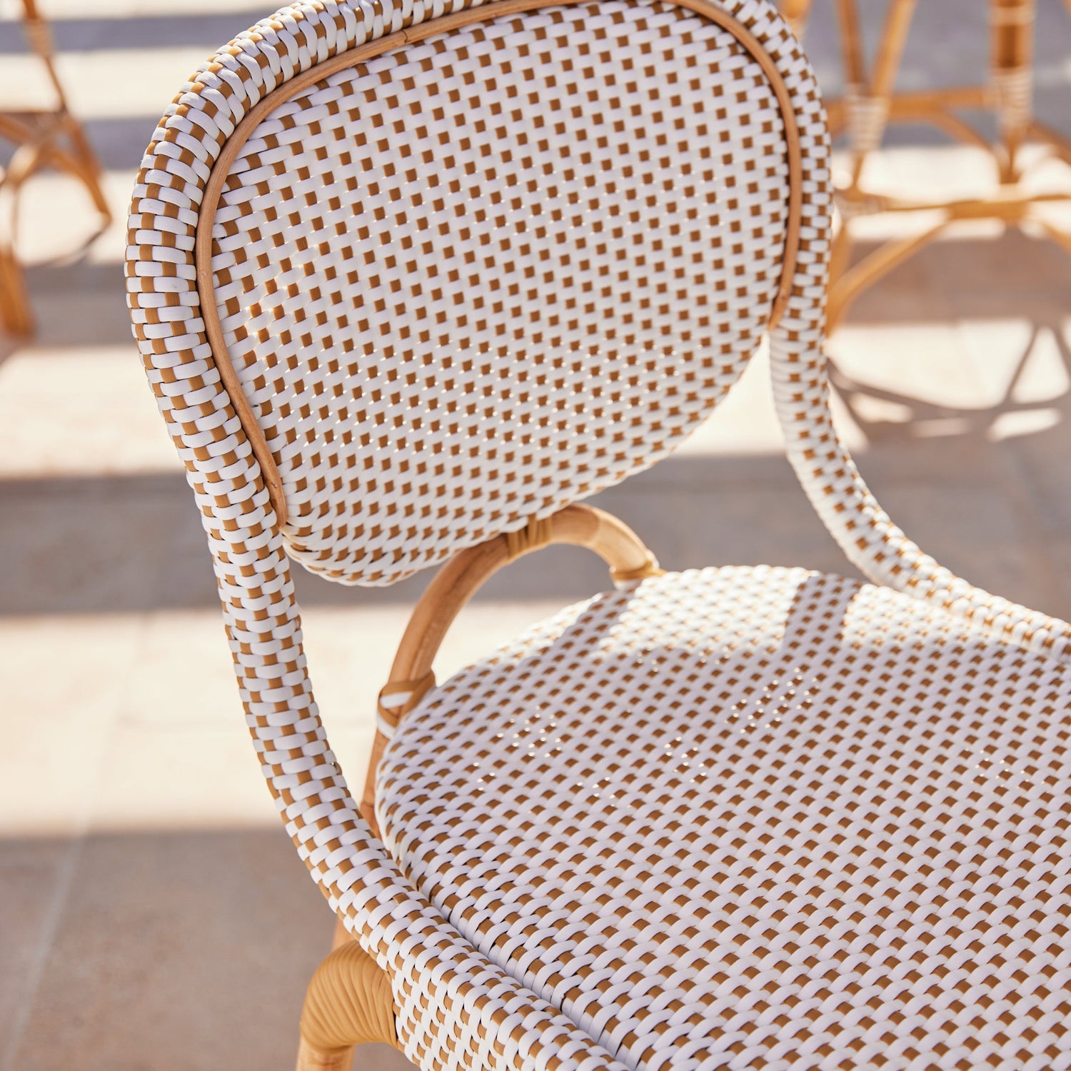 Wicker chair with checkered pattern on a sunny outdoor patio- Number 3
