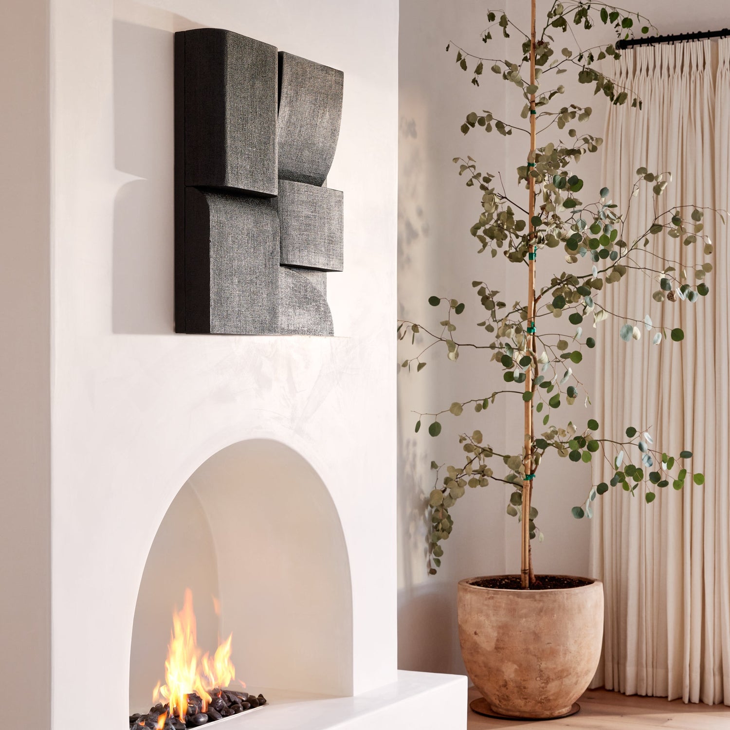 Modern living room with a white fireplace, decorative wall art, and a potted plant.- Number 2