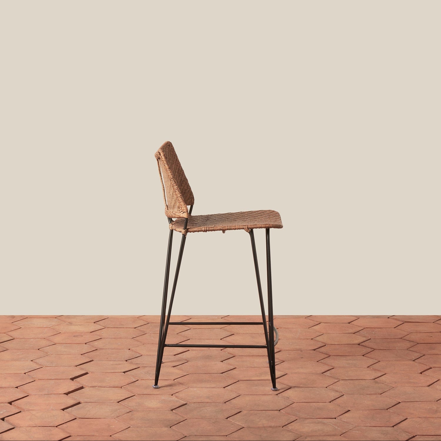 Bar stool with wicker seat and metal legs on a wooden floor.- Number 2