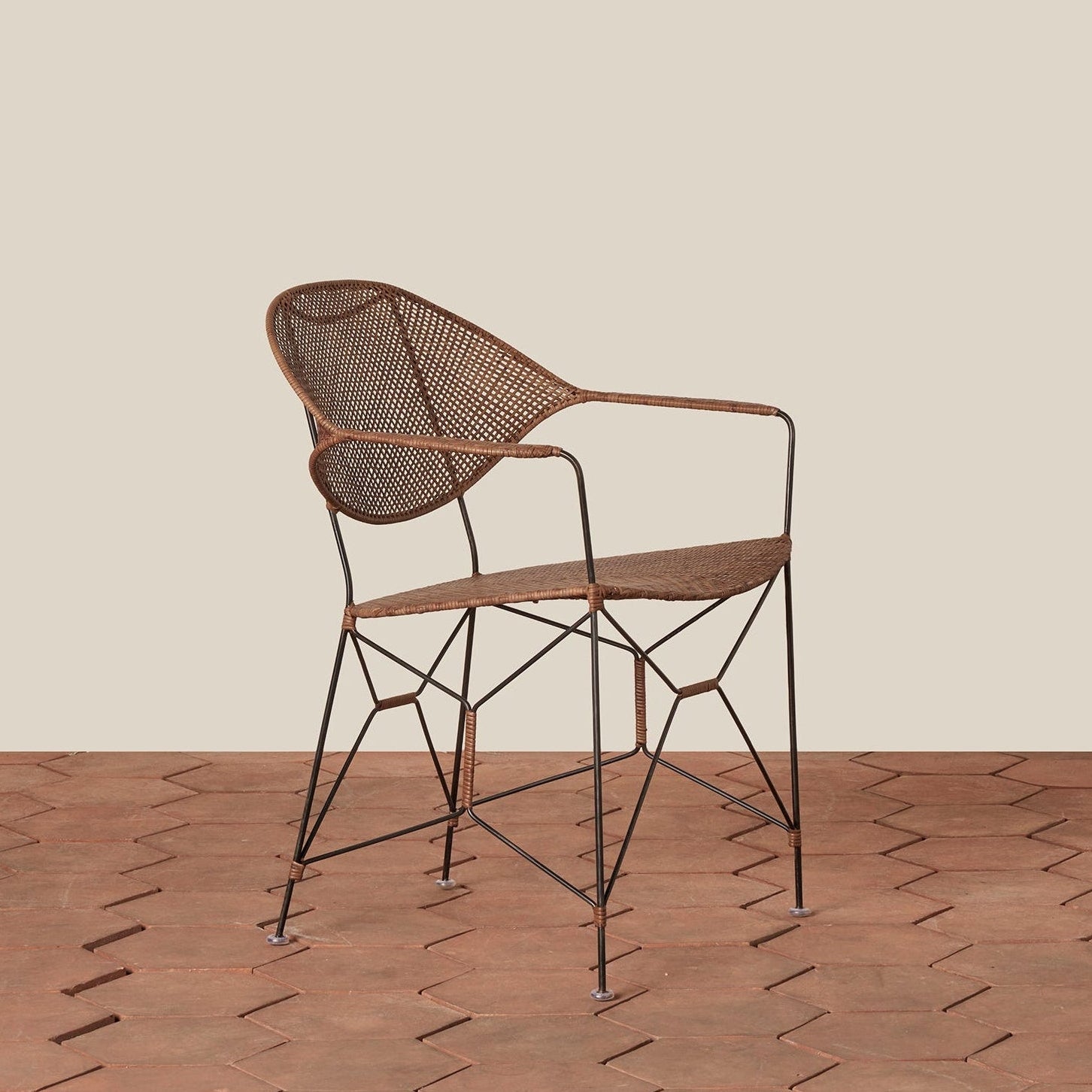 brown rattan and iron chair with pointed legs on tile floor against white background- Number 1