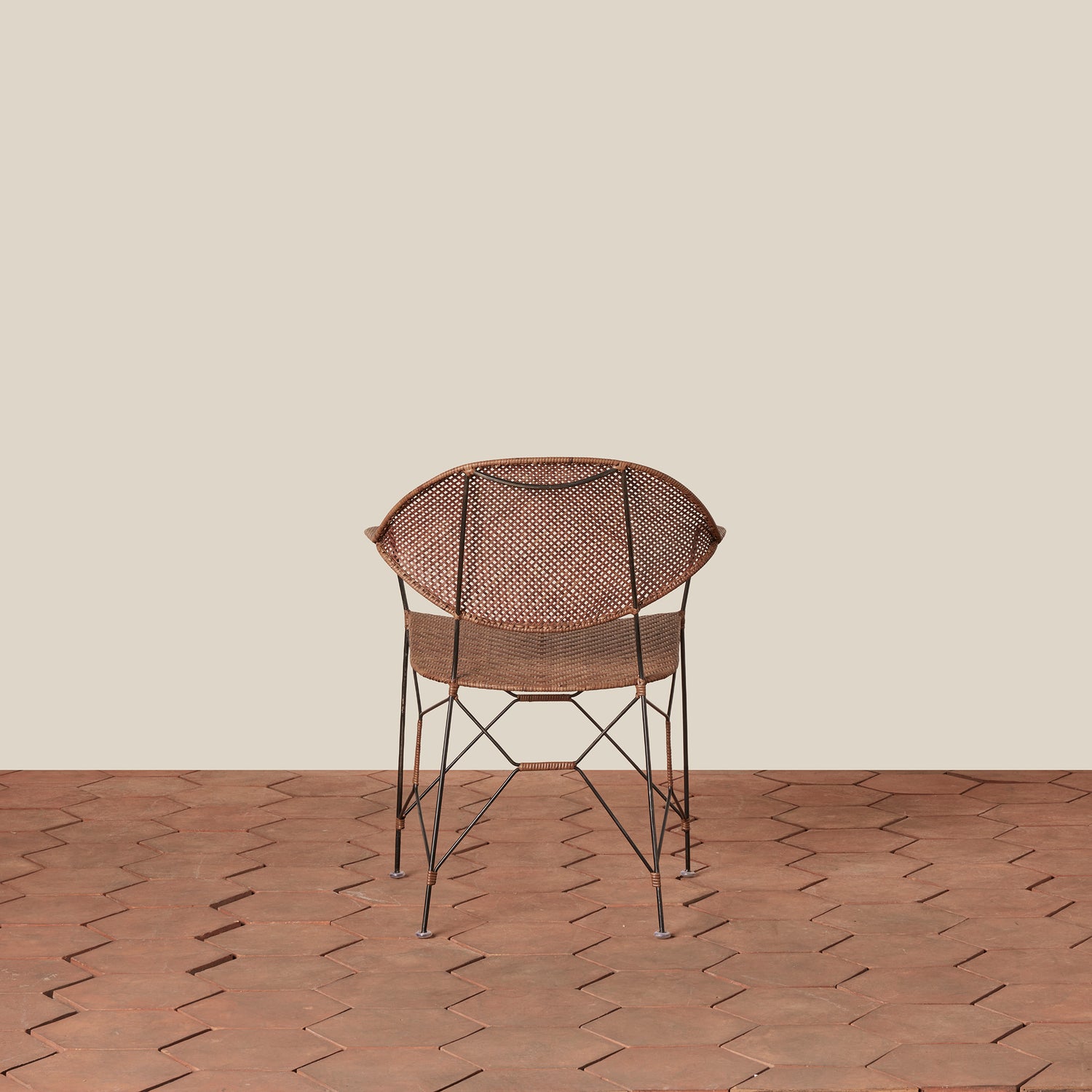 brown rattan and iron chair with pointed legs on tile floor against white background- Number 6