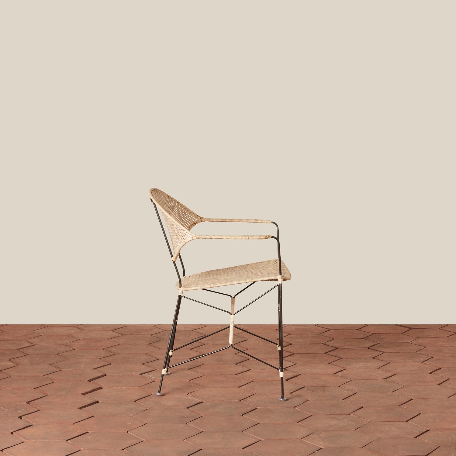 white and black rattan and iron chair with pointed legs on tiled floor against white background- Number 8