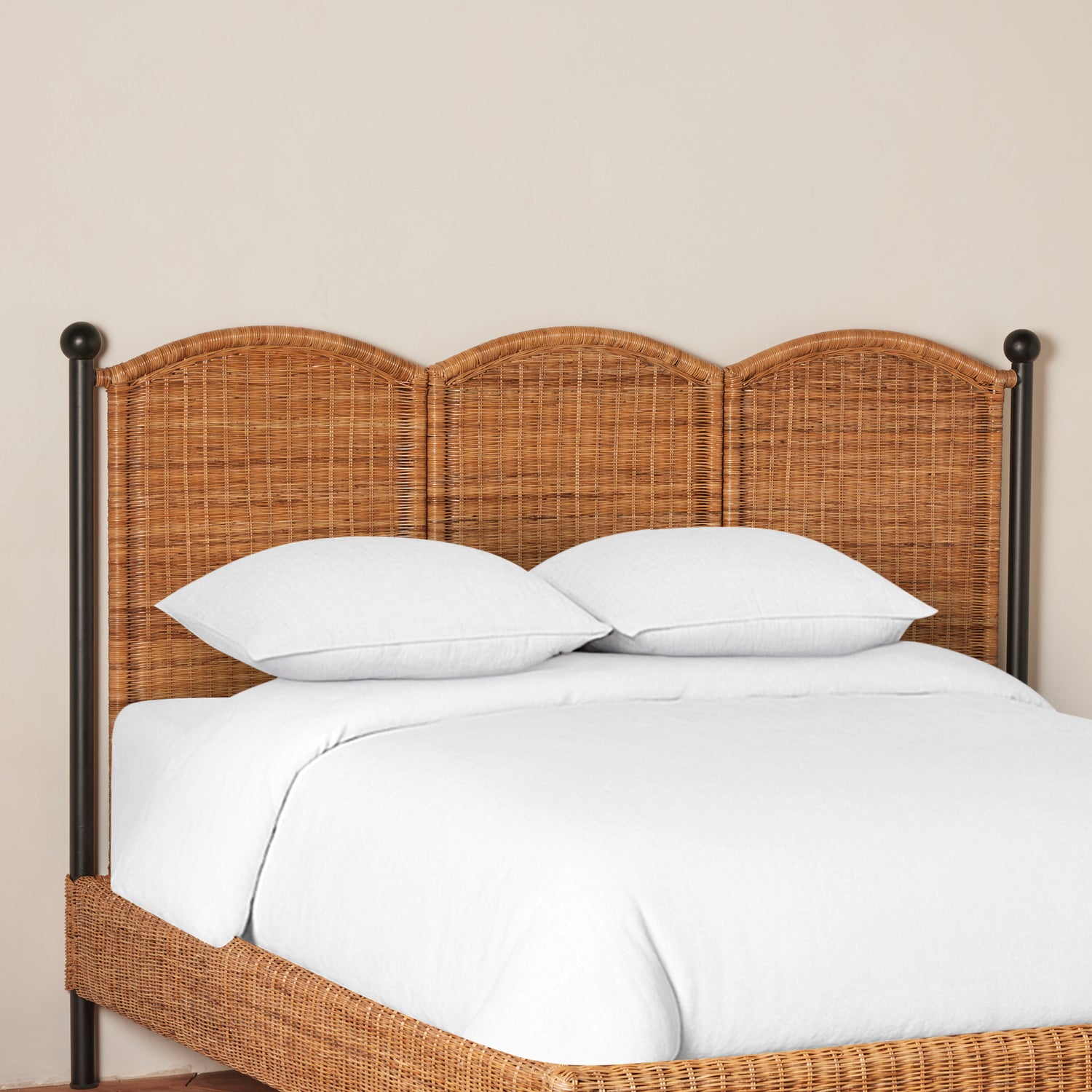 Bed with wicker headboard and white bedding against a beige wall- Number 7