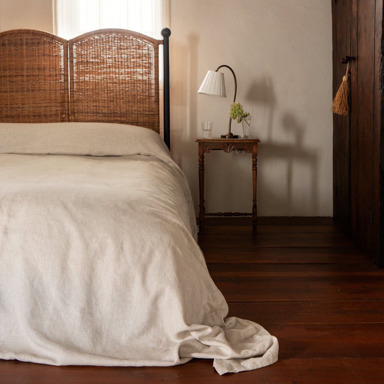 Bedroom with wooden headboard, white bedding, and side table with lamp.- Number 2