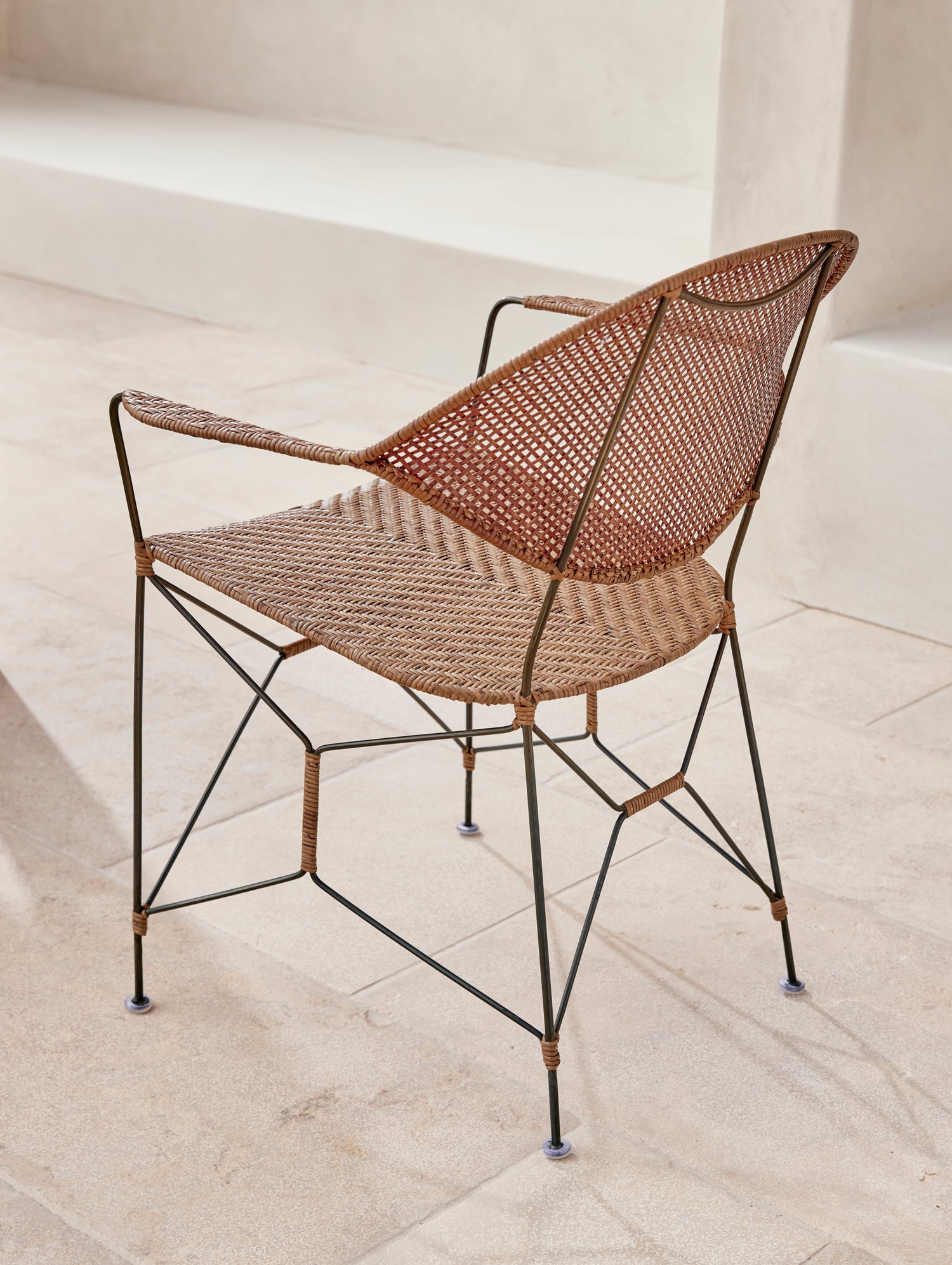 Woven chair with metal frame on a light stone floor- Number 3