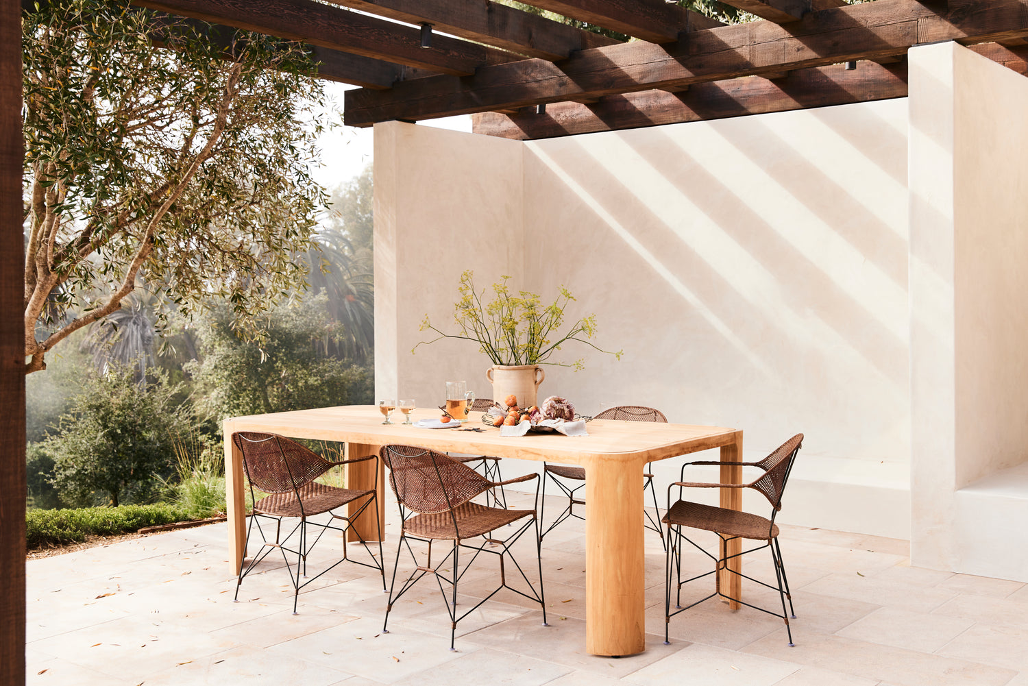 Outdoor dining area with a wooden table and chairs under a pergola.- Number 2