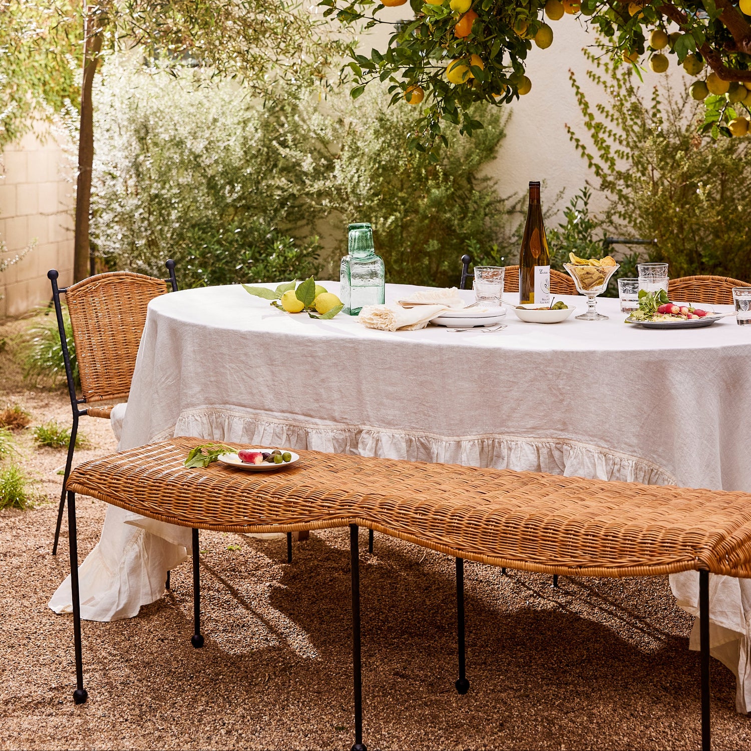 Outdoor dining setup with a table, chairs, and a bench under a lemon tree.- Number 2