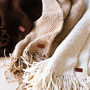 Three woven blankets in brown, beige, and white with fringes on a light background. - Number 5