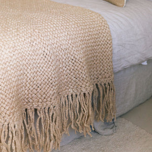 Beige woven blanket with fringes draped over a bed. - Number 2