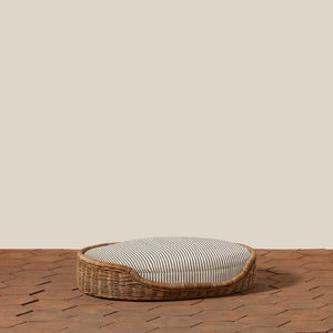 Round wicker pet bed with striped cushion on a wooden floor. - Number 13