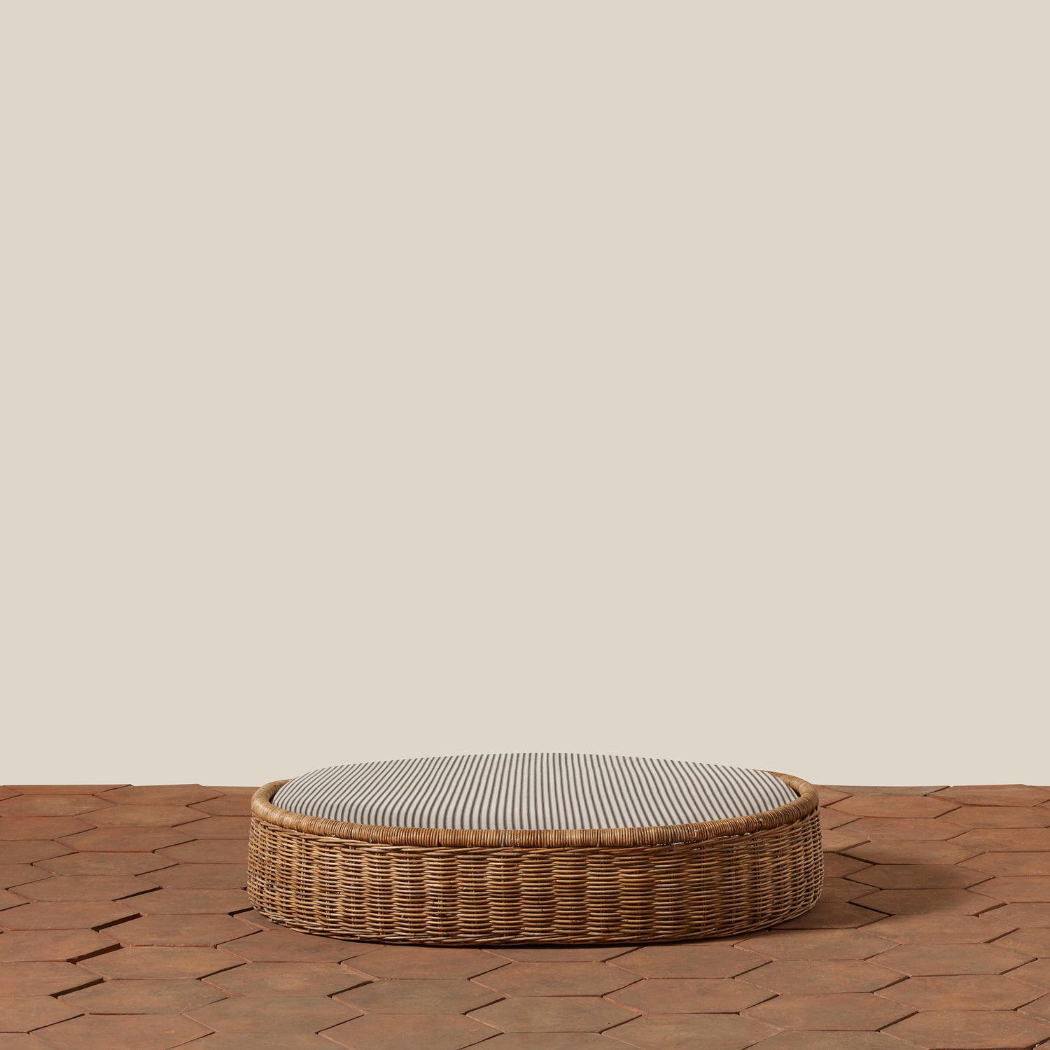 Round woven basket with a striped cushion on a wooden floor.- Number 15