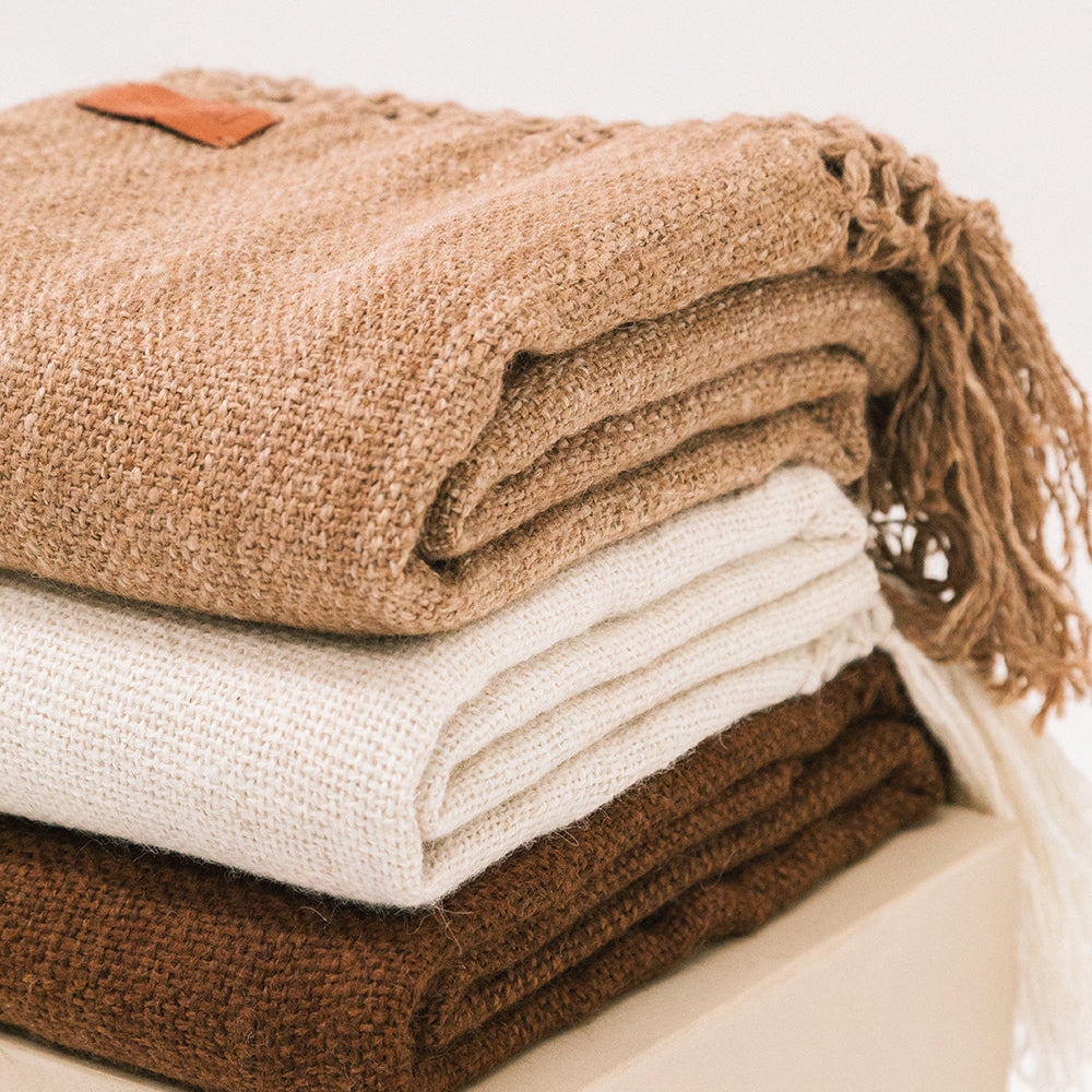 Stack of folded brown and white blankets on a light surface- Number 5