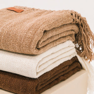 Stack of folded brown and white blankets on a light surface - Number 5