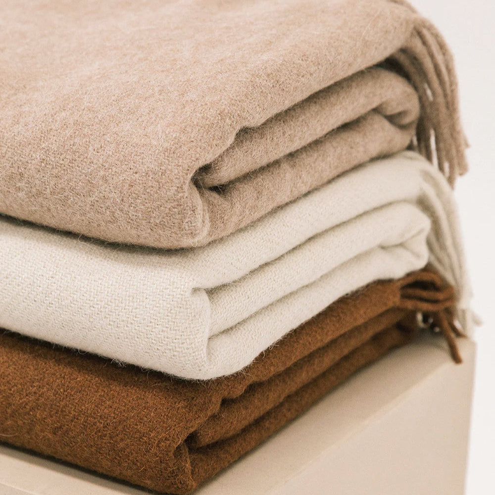 Stack of folded wool blankets in beige, brown, and white on a light background- Number 5