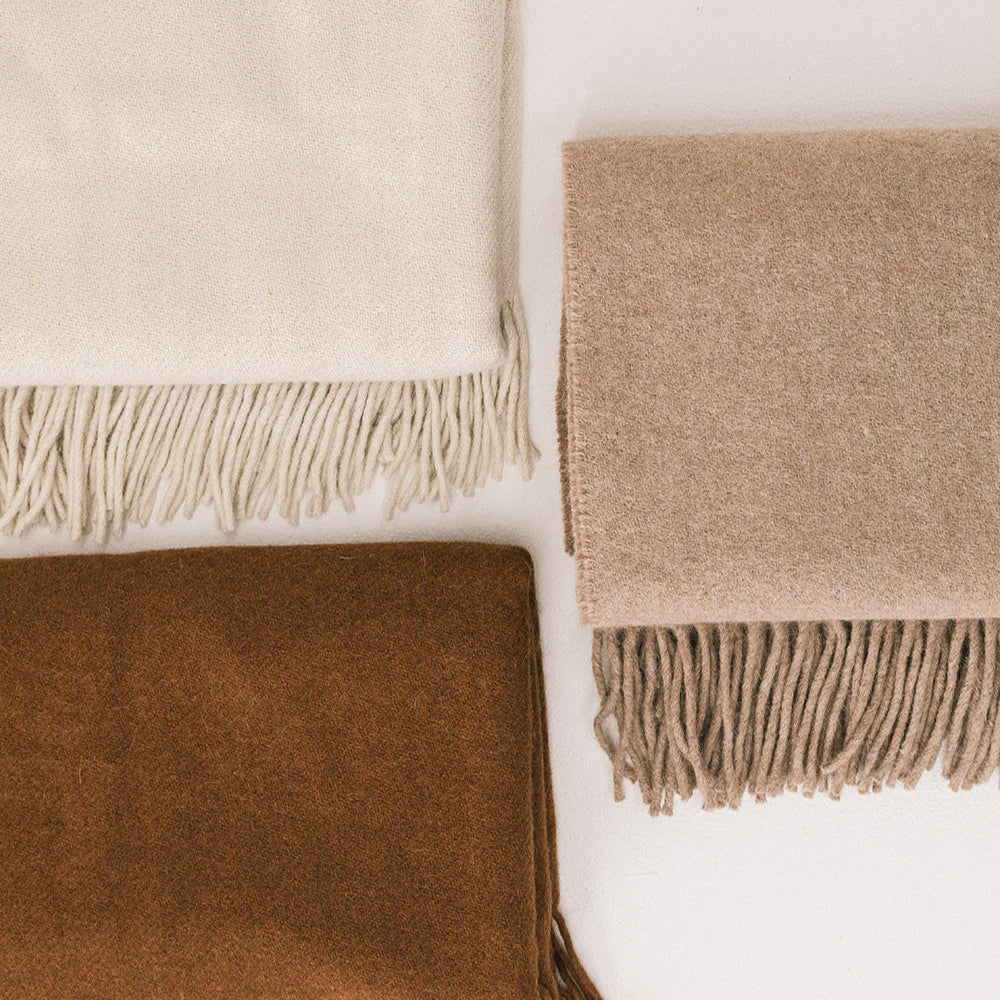 Three woven blankets in beige, brown, and cream on a white background- Number 6