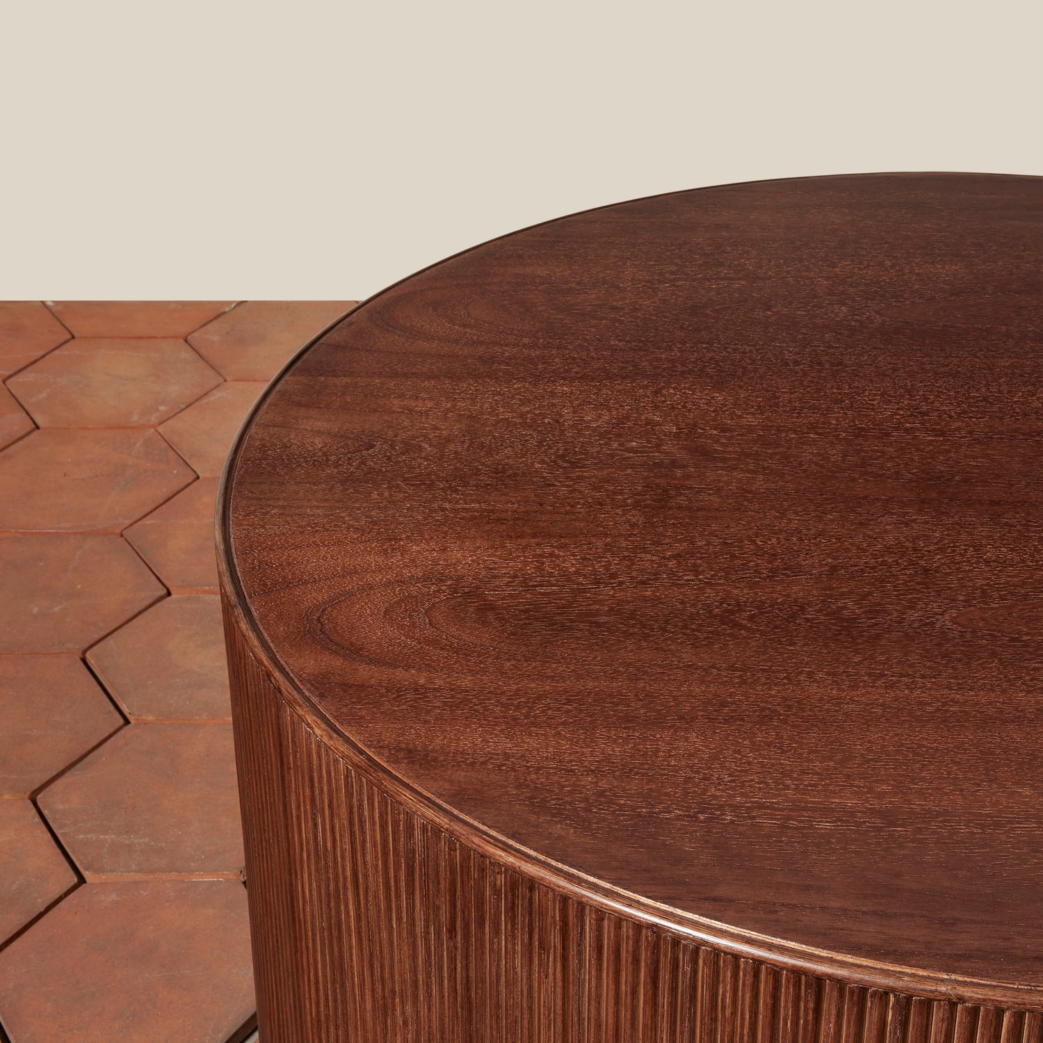 Round wooden table with a textured surface on a wooden floor.- Number 5