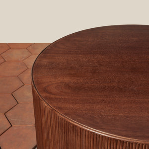 Round wooden table with a textured surface on a wooden floor. - Number 5