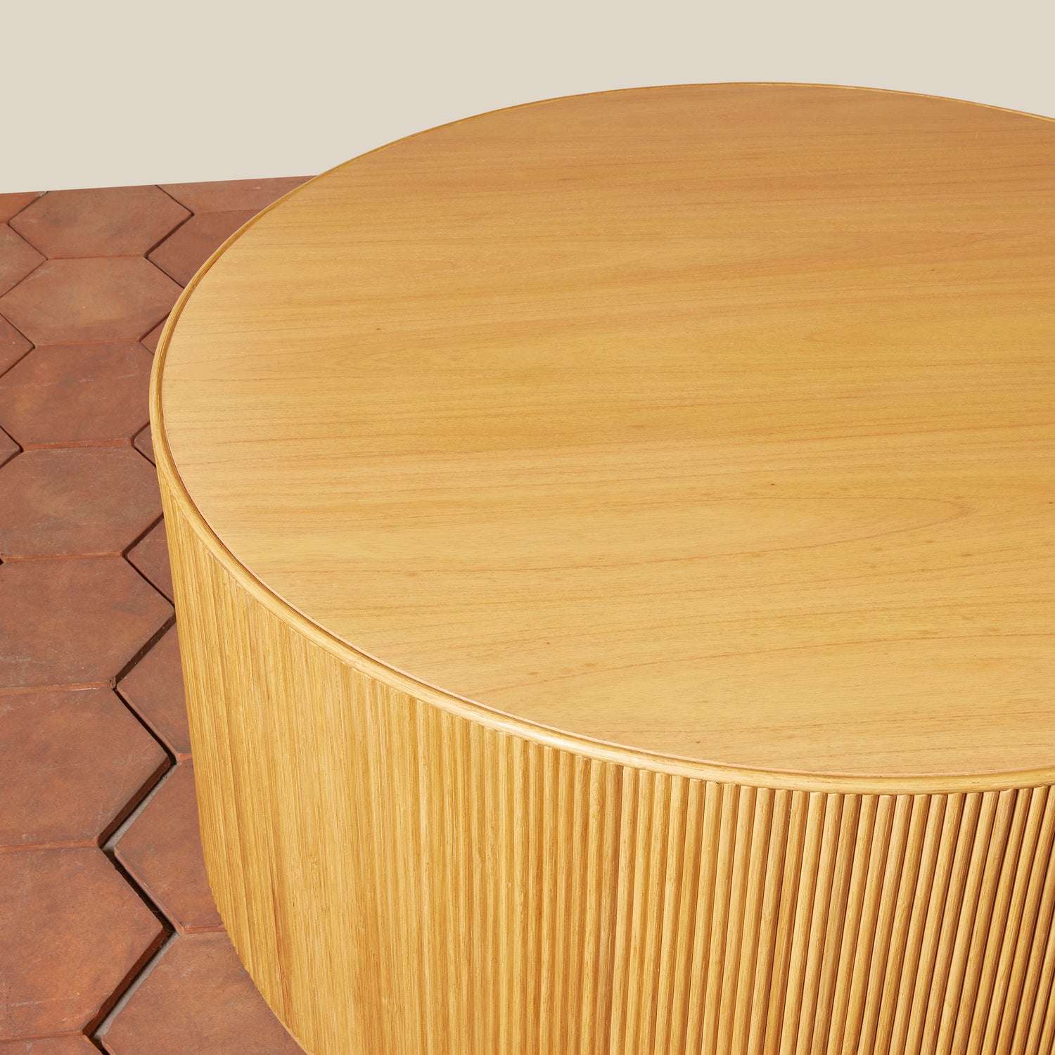 Round wooden table with a textured surface on a wooden floor.- Number 10