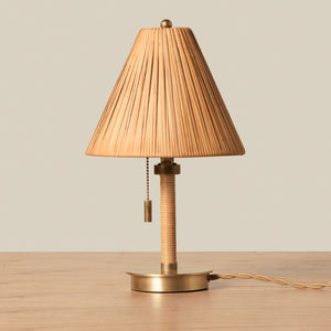 Small rattan table lamp with brass accents on wooden table against beige background - Number 1