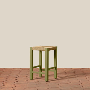 Green stool with woven seat on a wooden floor and beige wall background - Number 13