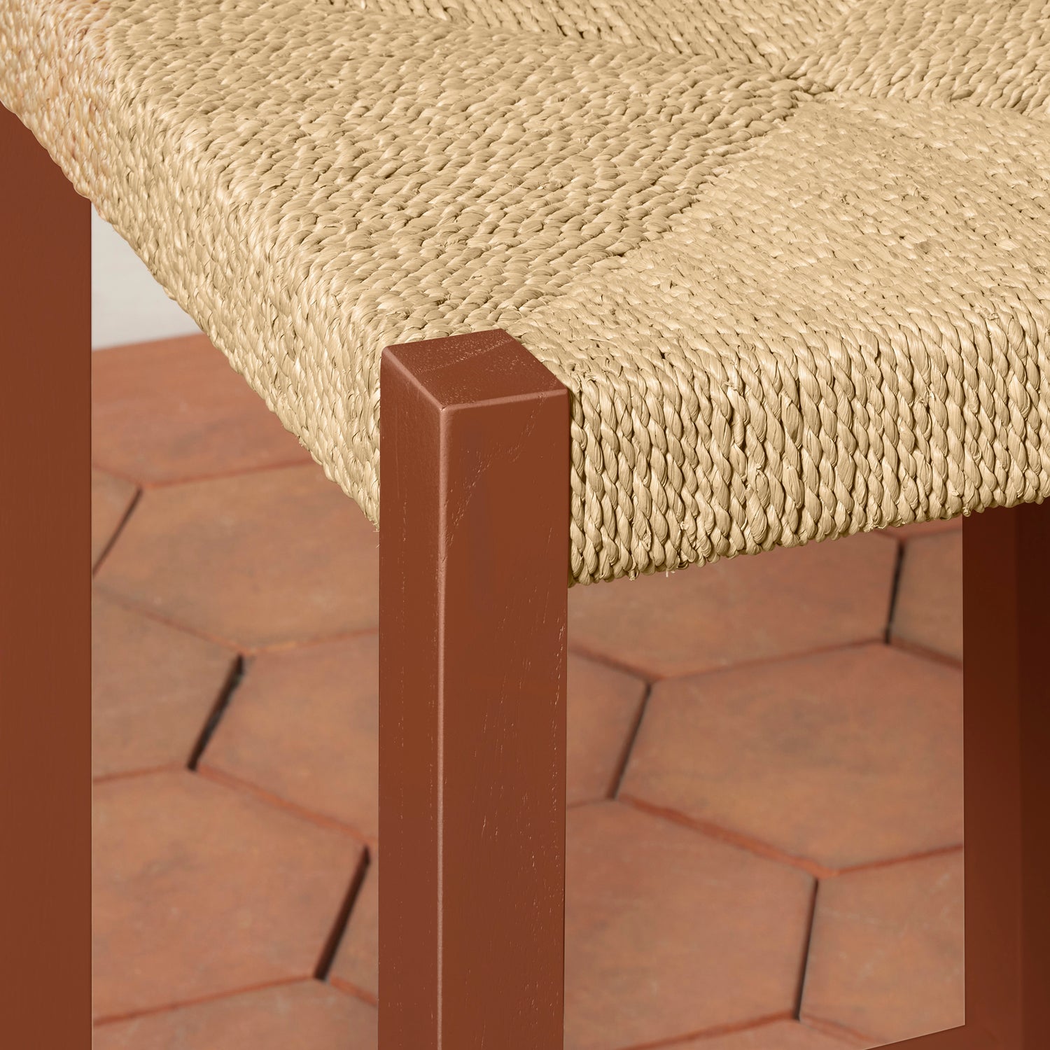 Close-up of a woven chair seat with a brown wooden frame on a brick surface.- Number 12