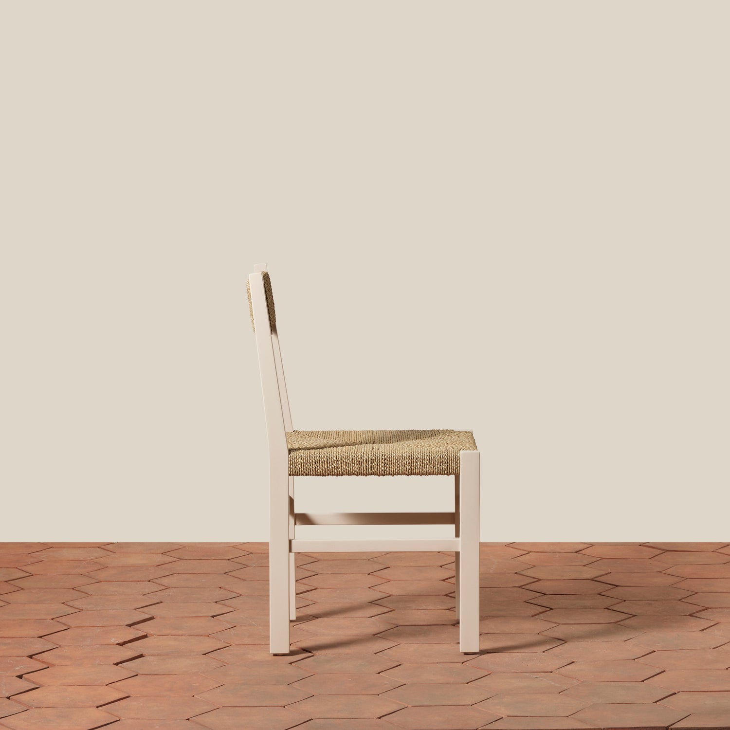 White chair with woven seat on a wooden floor and beige wall- Number 16
