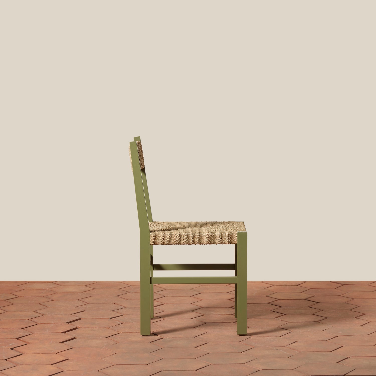 Green chair with woven seat on a wooden floor and beige wall background- Number 22