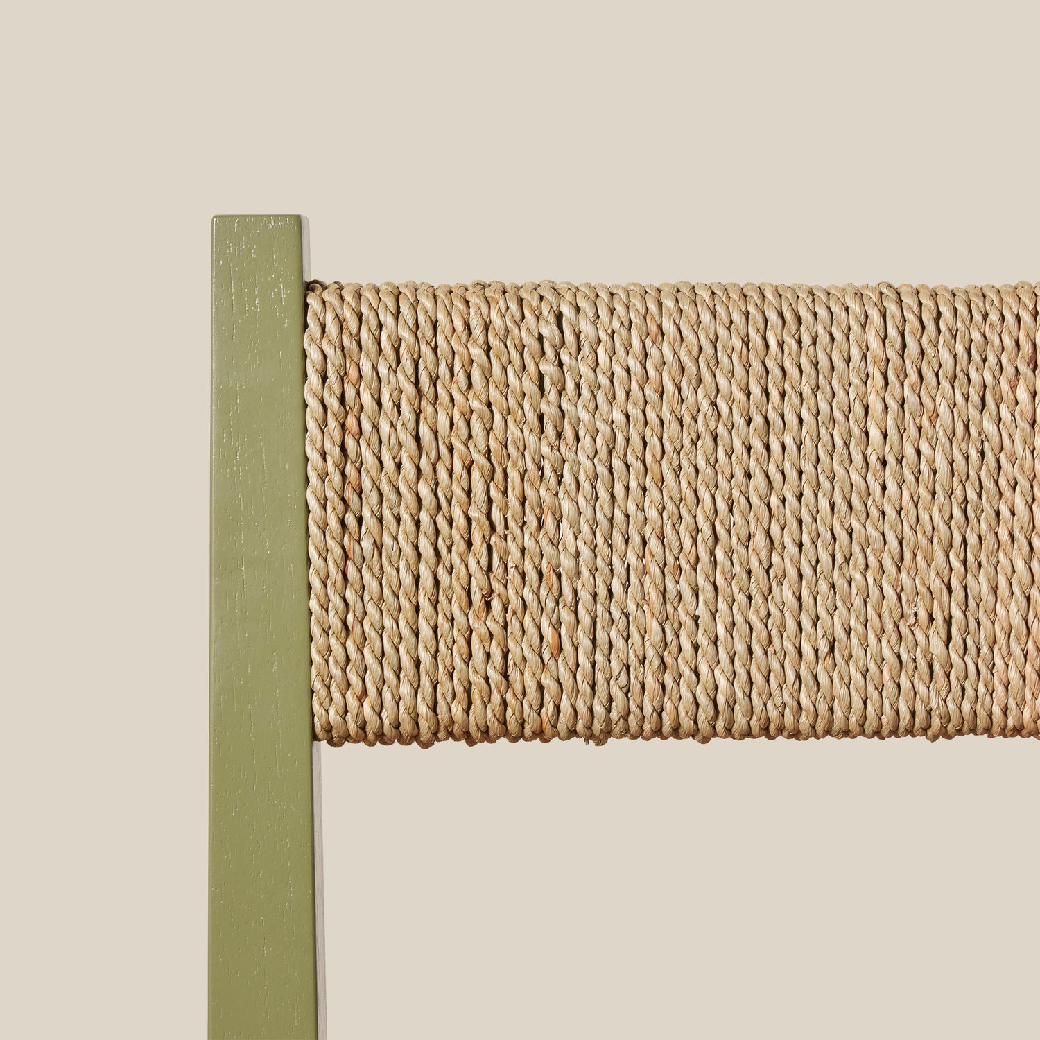 Close-up of a woven chair back with a green frame on a beige background- Number 25