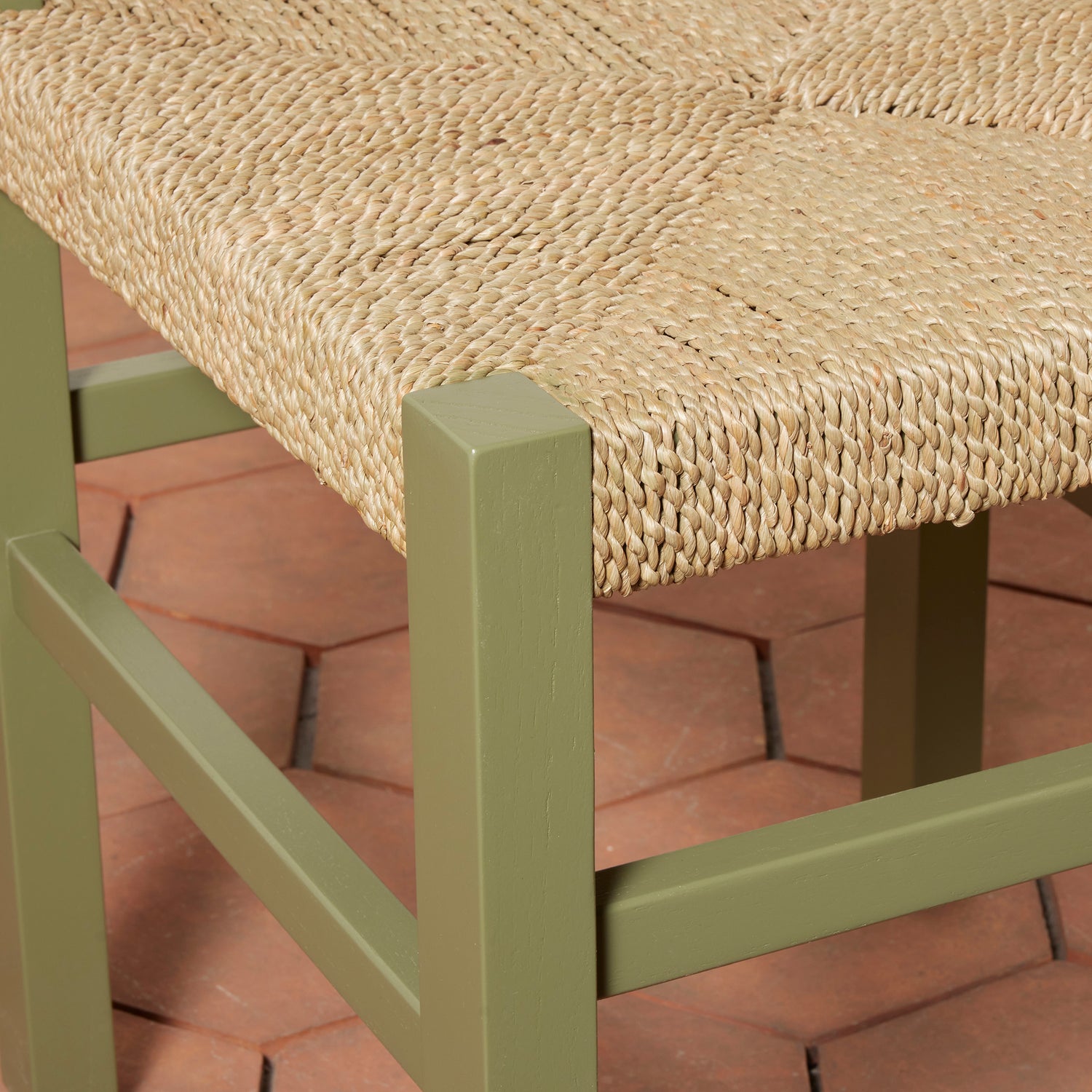 Close-up of a chair with a woven seat on a red brick surface- Number 26