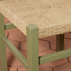 Close-up of a chair with a woven seat on a red brick surface - Number 26