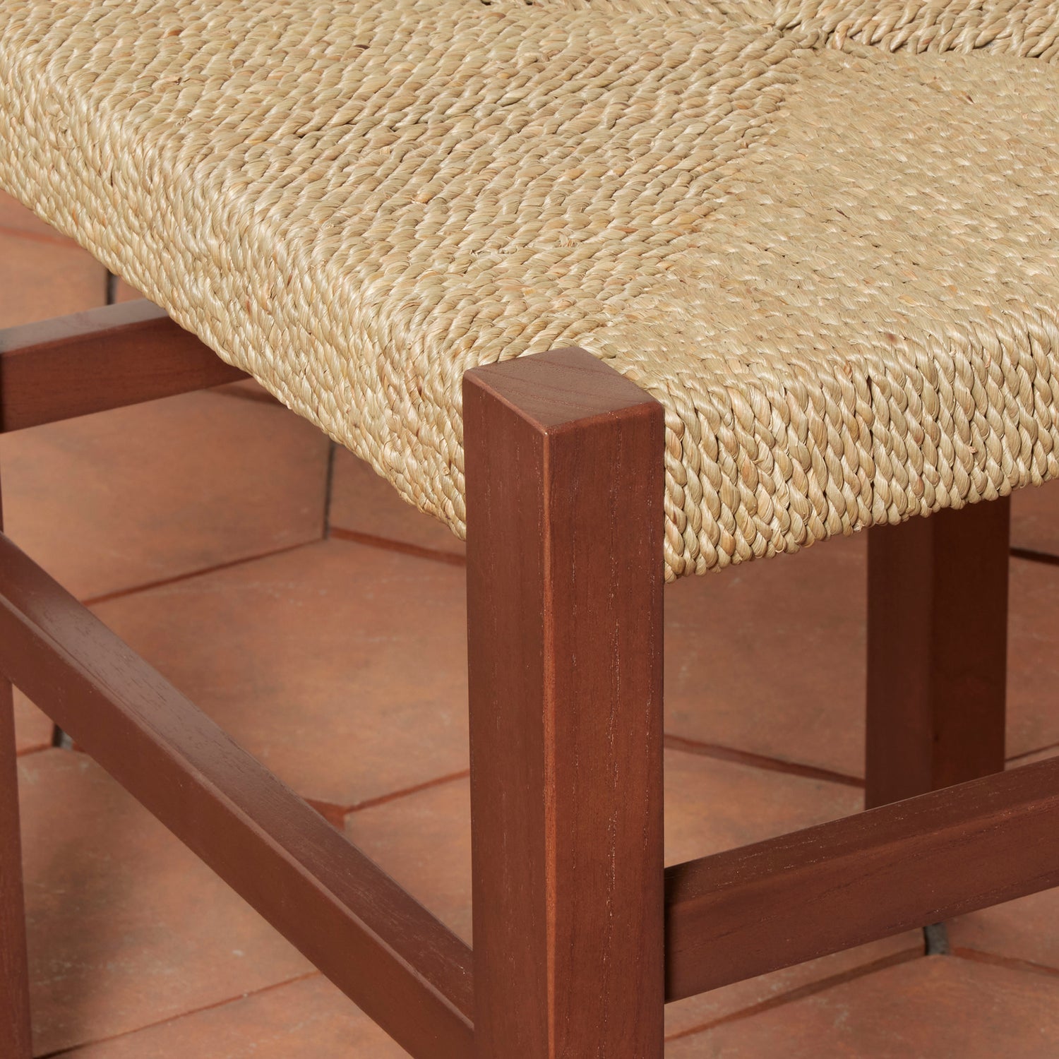 Close-up of a wooden chair with a woven seat on a terracotta floor.- Number 14