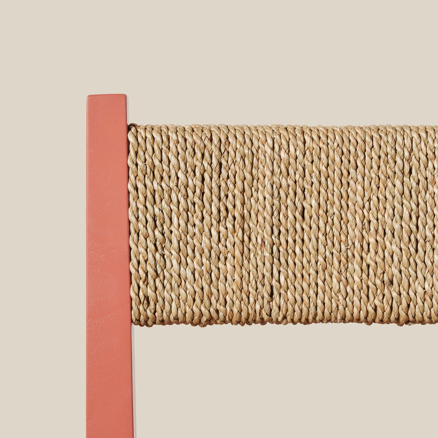 Close-up of a woven chair back with a pink border on a beige background- Number 7