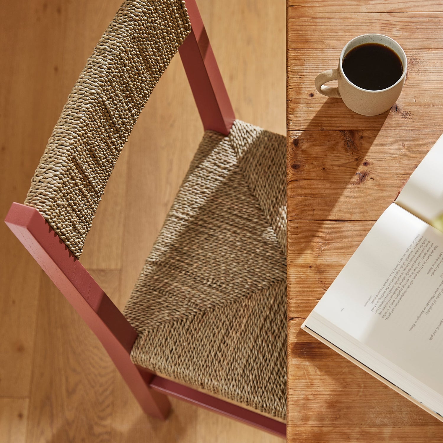 Wooden chair with a woven seat next to a wooden table with a cup and book- Number 3