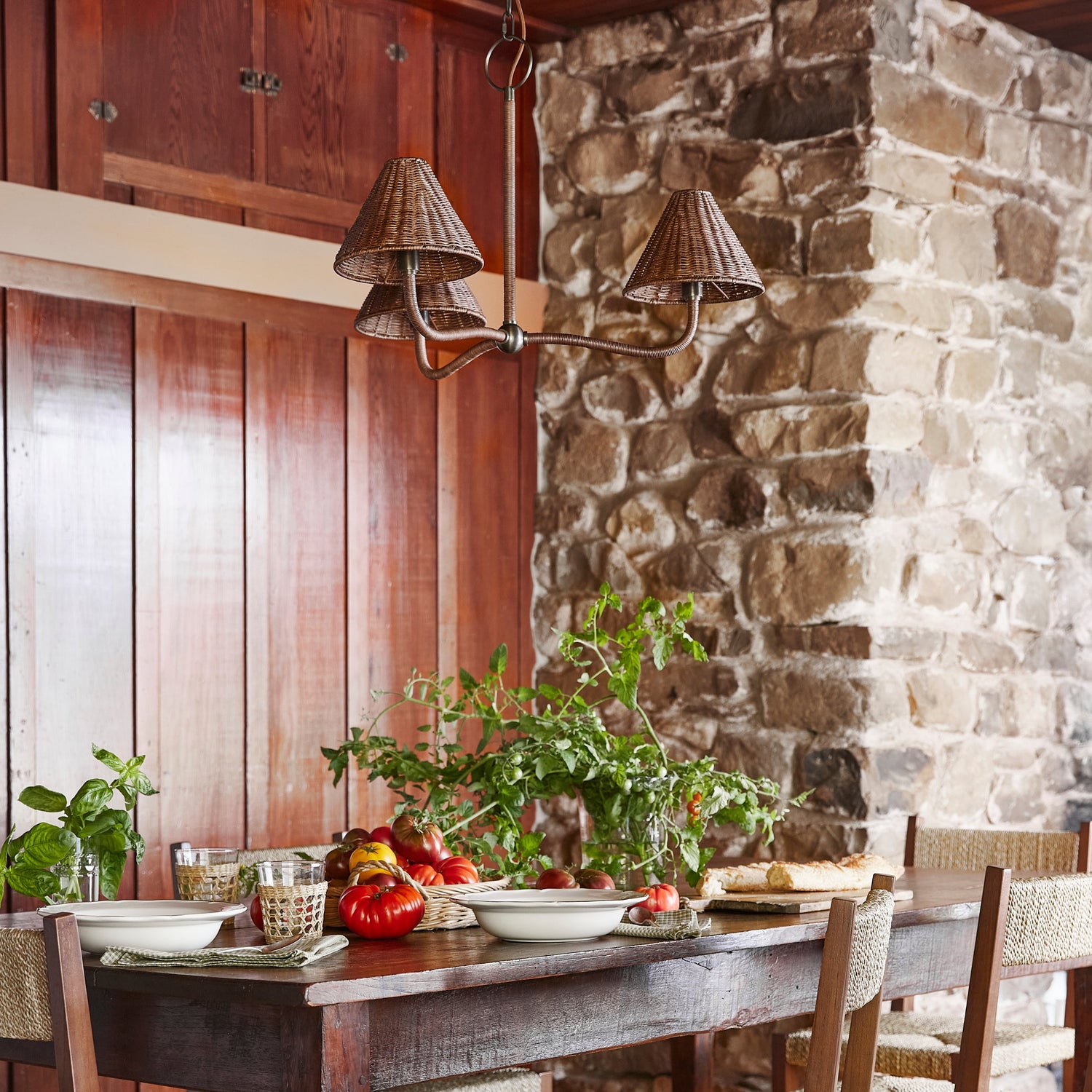 dark rattan chandelier against wood wall and stone fireplace, above table setting- Number 2
