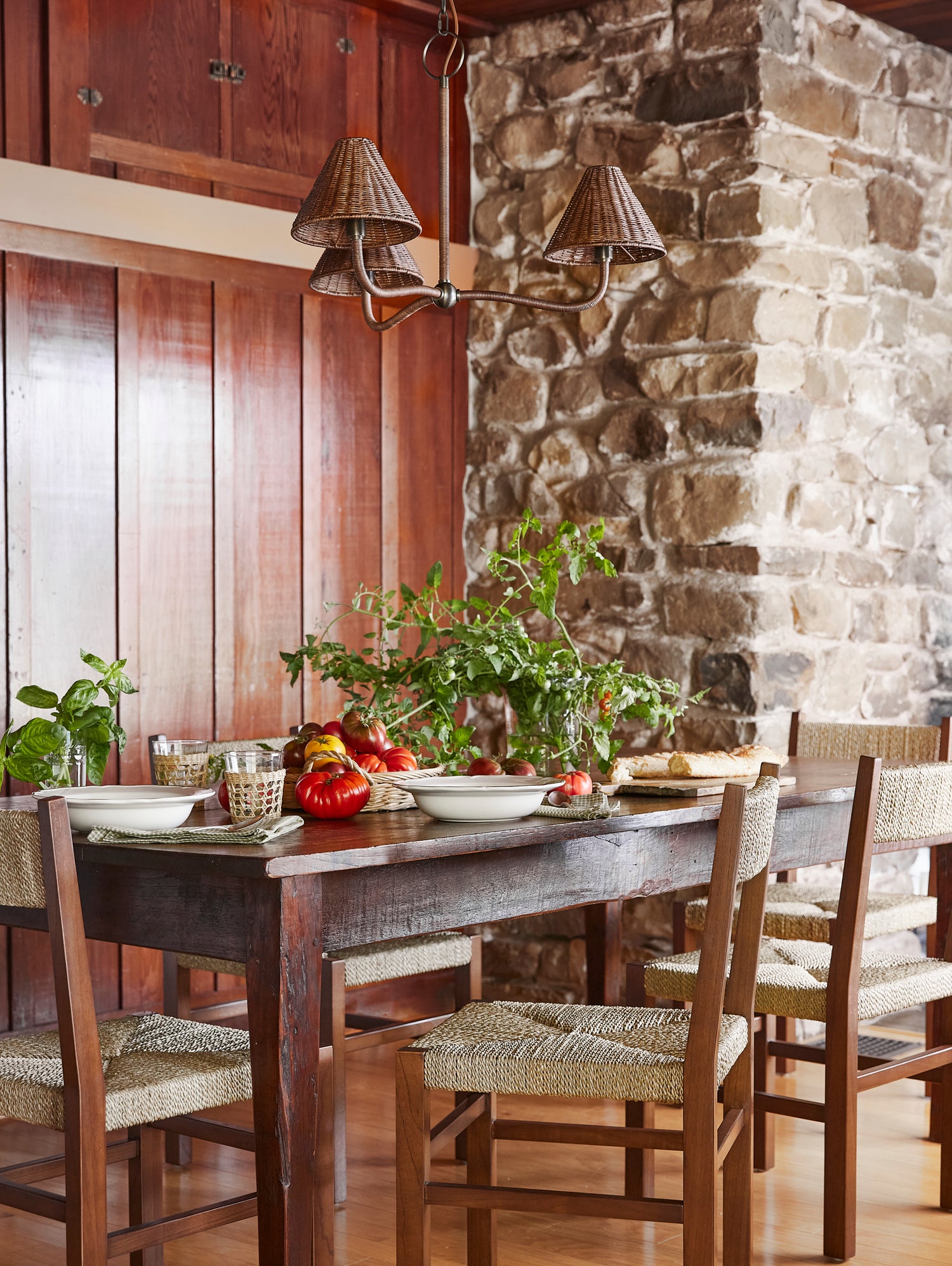 dark rattan chandelier against wood wall and stone fireplace, above table setting- Number 2