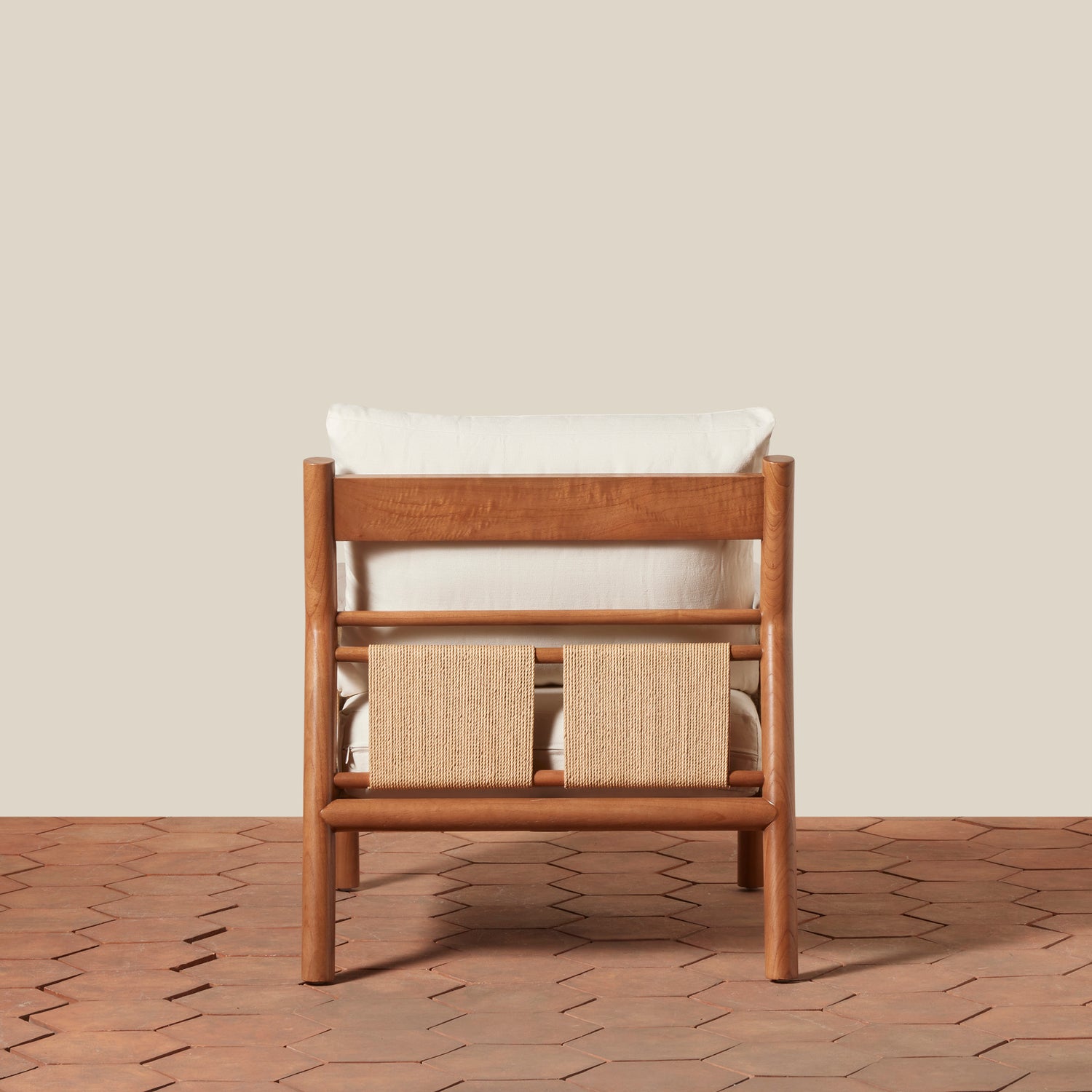 Wooden chair with white cushion and woven back on a wooden floor.- Number 4